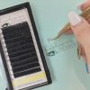 Hand using custom Lashes On Point tweezers to create a handcrafted Russian volume lash fan.